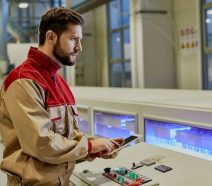 Travailleur masculin utilisant une tablette devant une machine de ligne de production automatisée dans une usine