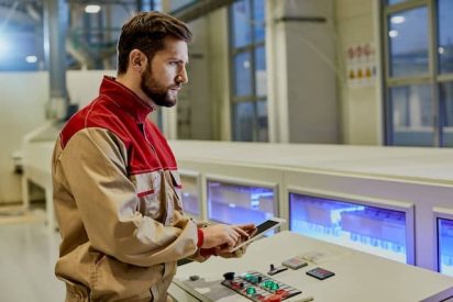 Travailleur masculin utilisant une tablette devant une machine de ligne de production automatisée dans une usine