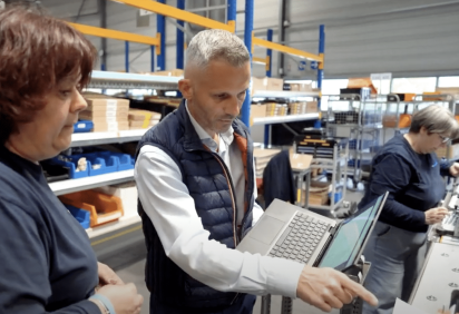 Le directeur d'usine de Socomec montre un indicateur à une opératrice en usine