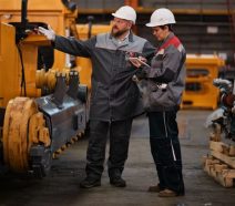 Deux personnes debout dans une usine, discutent