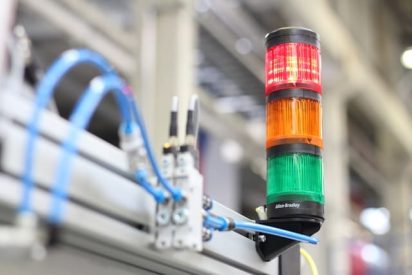An andon light with red, orange, and green stacked on a machine as a visual cue on the shop floor.