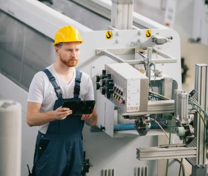 Manufacturer digitally noting machine stoppage in manufacturing before conducting a 5 whys problem solving root cause analysis.