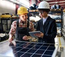 Lean manufacturers on the shop floor putting Genchi Genbutsu into practice by going to gemba, collaborating, and documenting observations on an ipad.