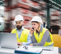 Two engineers on the factory floor collaboratively problem solving with digital tools putting the 8d method into practice for continuous improvement.