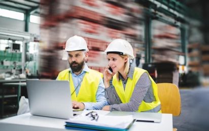 Two engineers on the factory floor collaboratively problem solving with digital tools putting the 8d method into practice for continuous improvement.