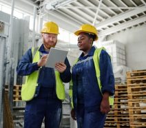 Opérateurs industriels analysant leurs objectifs opérationnels SMART sur un tableau de management visuel digital dans une usine.