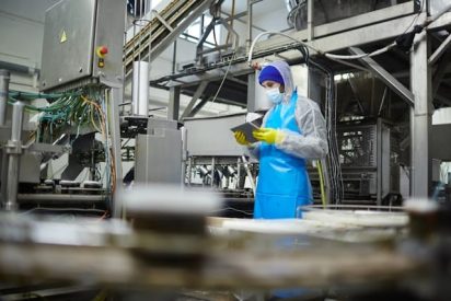 Manufacturing worker in PPE on the shop floor performing FMEA using digital tools to identify potential process risks.