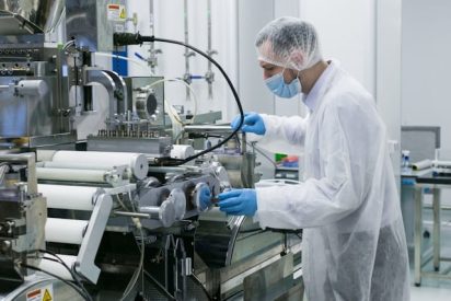 Pharma factory quality employee ensuring GMP documentation and production controls are in place on shop floor to ensure consistent, compliant manufacturing and traceability.