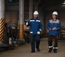 Plant manager performing a management by walking around (MBWA) visit on a manufacturing shop floor while speaking with operator.