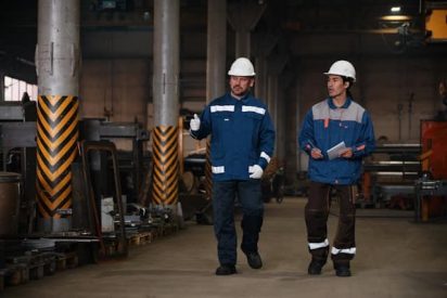 Plant manager performing a management by walking around (MBWA) visit on a manufacturing shop floor while speaking with operator.