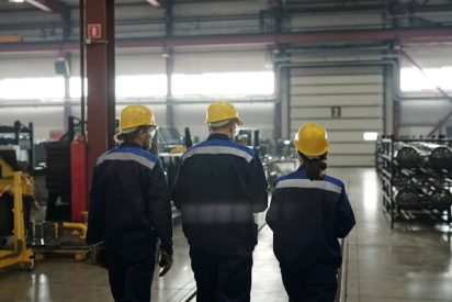 Factory workers collaborating on the shop floor in a manufacturing plant, illustrating knowledge sharing and operational teamwork.