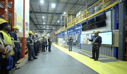 Organized factory floor showing efficient flow and a digital performance dashboard, illustrating a modern lean manufacturing system in practice for waste reduction.